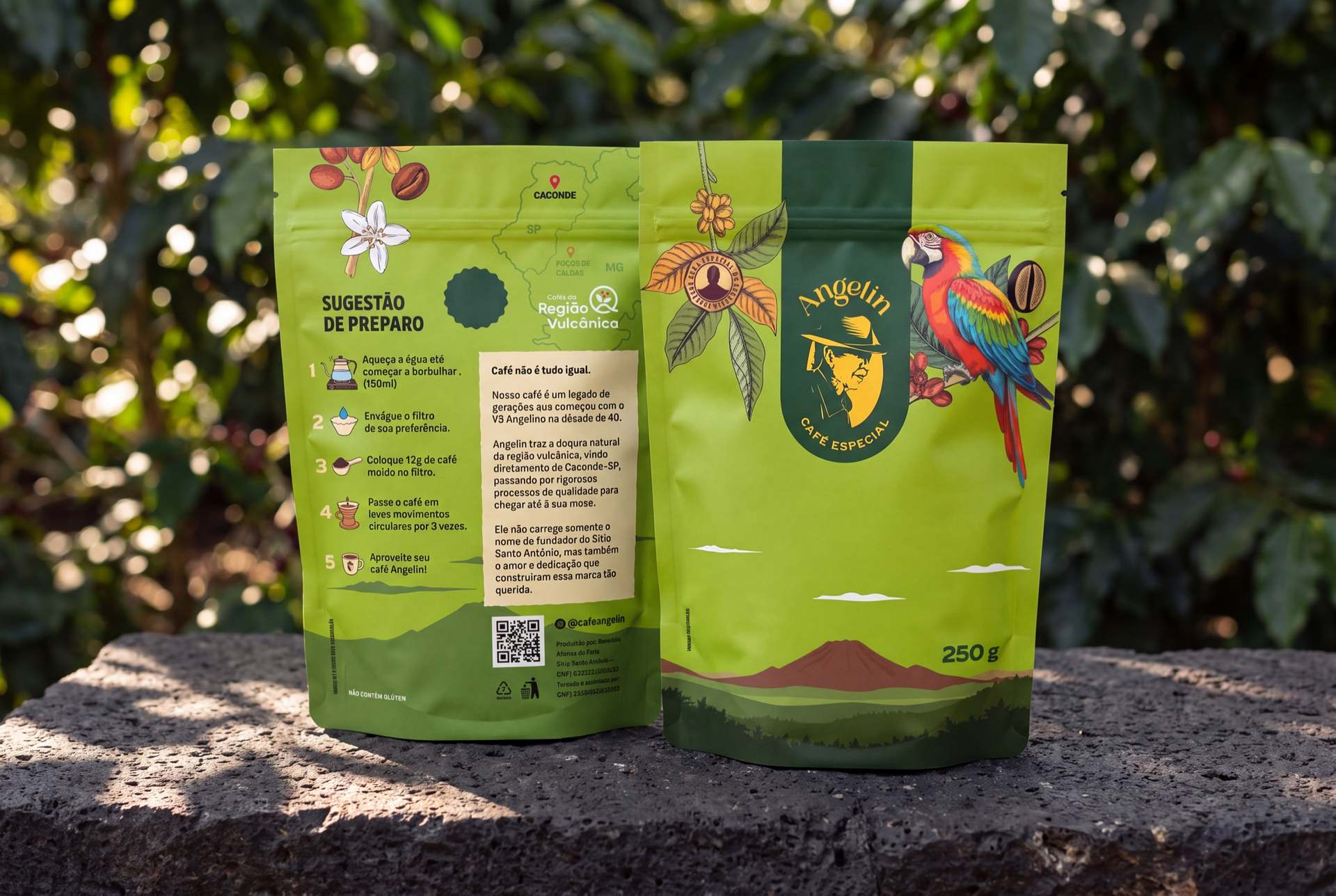 Frente e verso do pouch verde de café especial Angelin 250 g sobre pedra, com vegetação ao fundo.