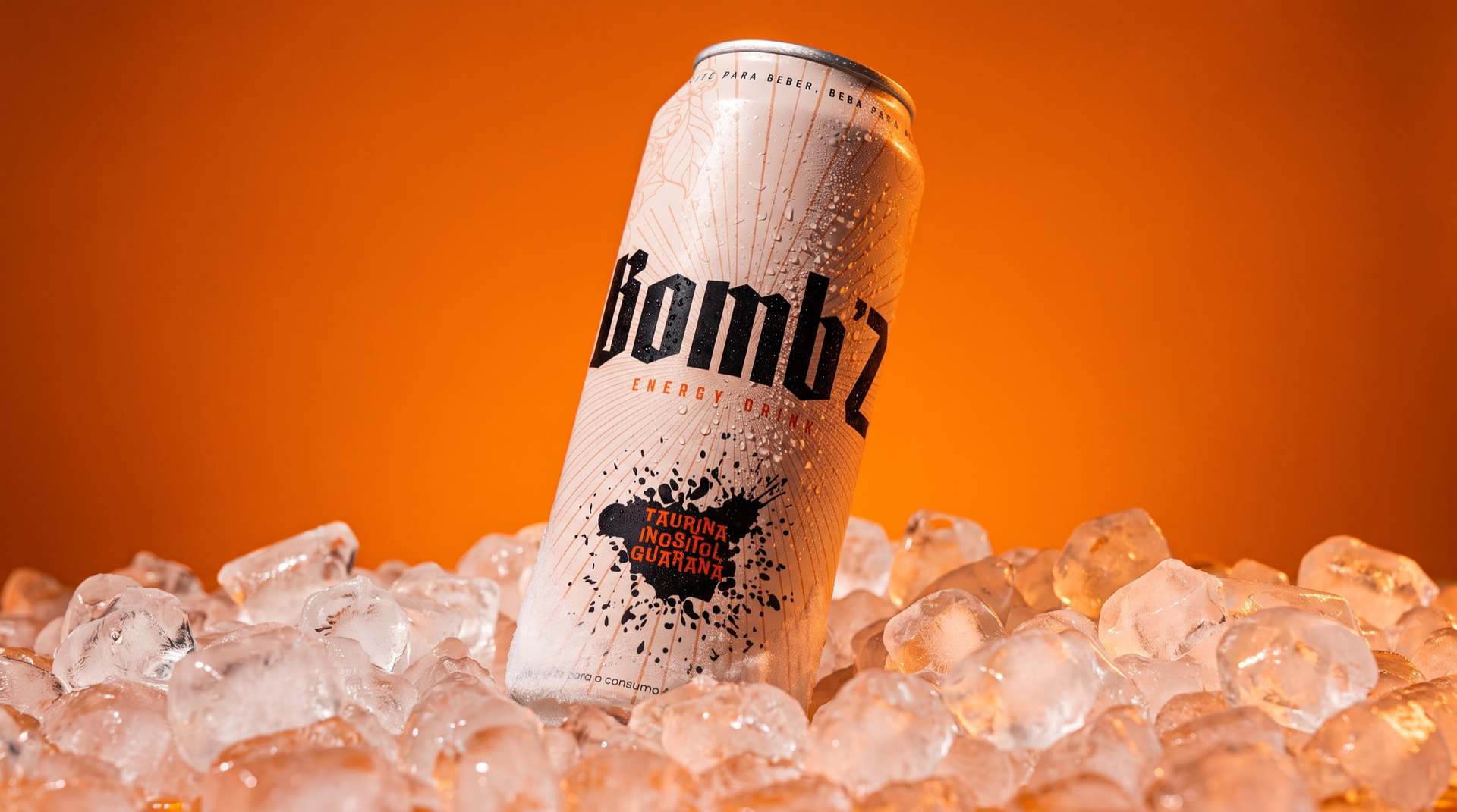 Lata de energético Bomb'z sobre gelo, com fundo laranja e gotas de condensação.